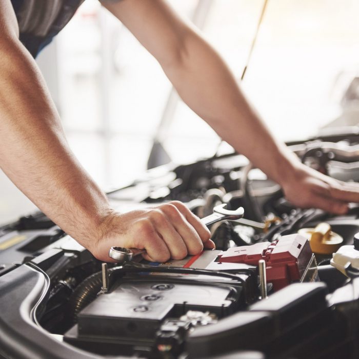 Auto mechanic working in garage. Repair service.
